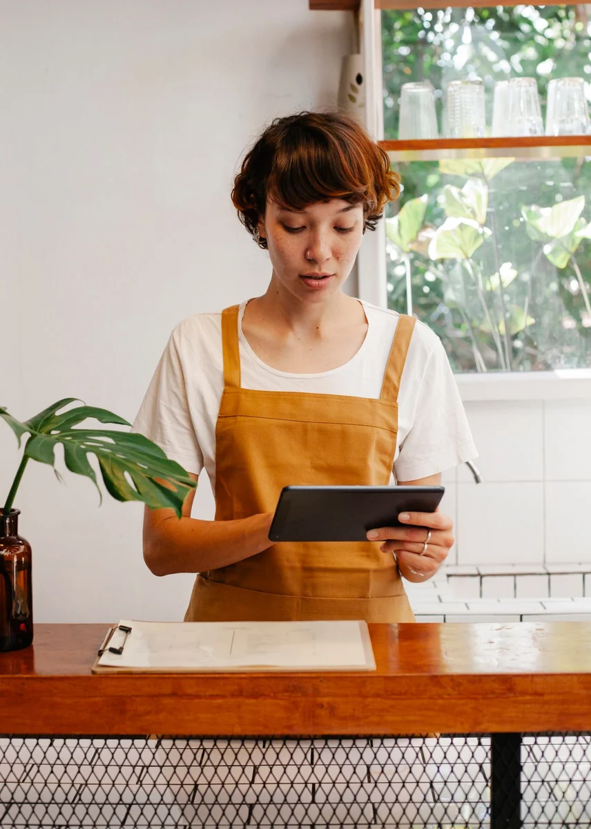 Trabajadora de una cafetería utilizando una tableta en el mostrador